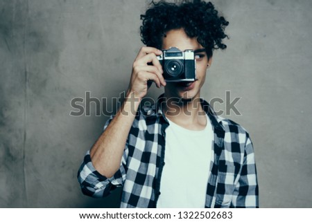 A man with a camera and a plaid shirt                     