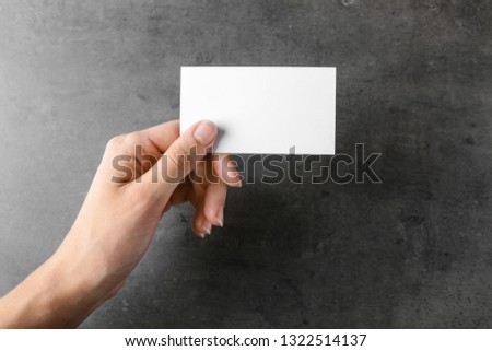 Female hand with blank business card on grey background