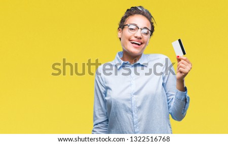 Young african american girl holding credit card over isolated background with a happy face standing and smiling with a confident smile showing teeth