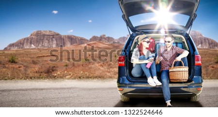 Summer car trip on USA road and two oung lovers. Free space for your decoration. Blue big car and summer sun light. 