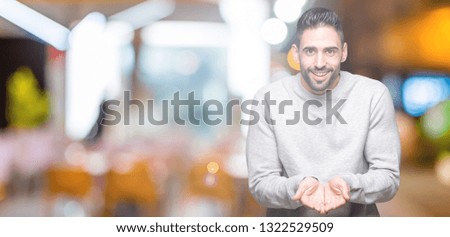 Young handsome man wearing sweatshirt over isolated background Smiling with hands palms together receiving or giving gesture. Hold and protection