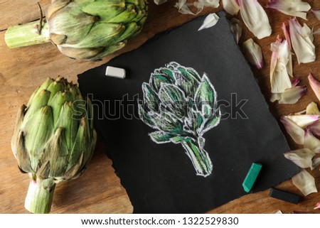 Tasty raw artichokes with picture on wooden table