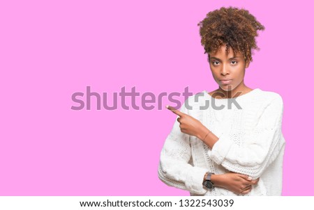 Beautiful young african american woman wearing winter sweater over isolated background Pointing with hand finger to the side showing advertisement, serious and calm face