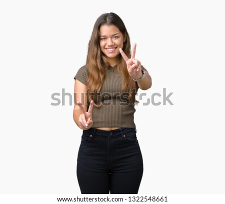 Young beautiful brunette woman over isolated background smiling looking to the camera showing fingers doing victory sign. Number two.
