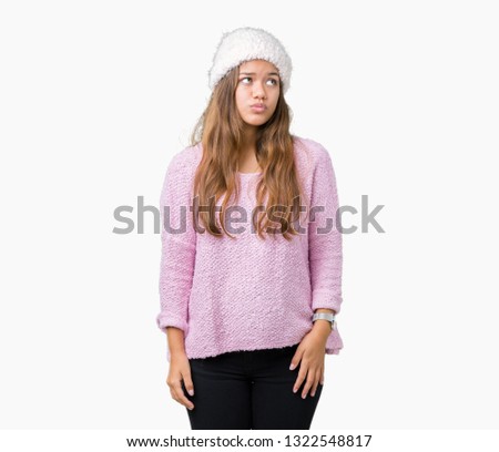 Young beautiful brunette woman wearing sweater and winter hat over isolated background making fish face with lips, crazy and comical gesture. Funny expression.