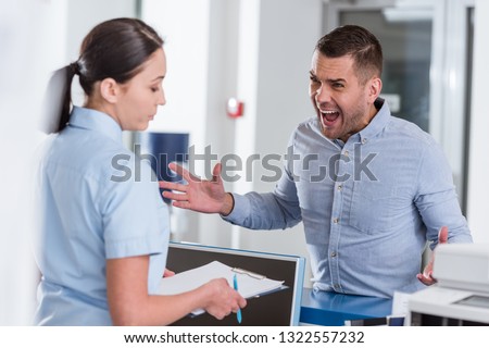 Aggressive man yelling at nurse in clinic Royalty-Free Stock Photo #1322557232
