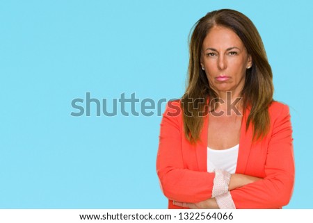 Beautiful middle age business adult woman over isolated background skeptic and nervous, disapproving expression on face with crossed arms. Negative person.