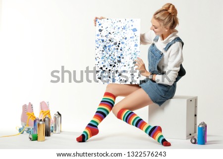 Woman with vintage roller skates, spray paint cans and beautiful picture on white background
