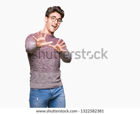 Young handsome man wearing glasses over isolated background afraid and terrified with fear expression stop gesture with hands, shouting in shock. Panic concept.