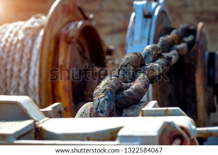 Steel anchor chains caked with rust at an industrial port facility, anchor chains roll-in strength with winch motor holding the ship in safe position 