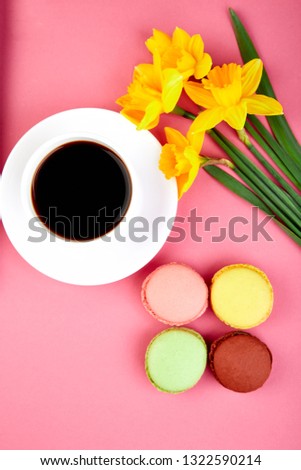 Colorful flat lay with flowers narcissus and sweets or cake macaroons and cup of coffee . Spring concept.  Good morning. Breakfast. Woman or mother Day. Flat lay.

