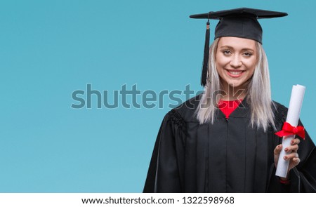 Young blonde woman wearing graduate uniform holding degree over isolated background with a happy face standing and smiling with a confident smile showing teeth