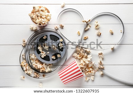Composition with film reel and popcorn on wooden background