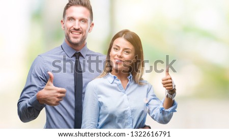 Young workers business couple over isolated background doing happy thumbs up gesture with hand. Approving expression looking at the camera with showing success.