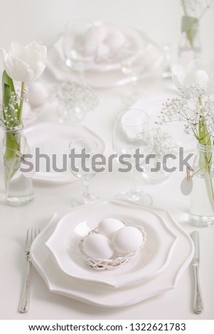 Happy Easter! Decor and table setting of the Easter table with white tulips and dishes of white color.  Selective focus.