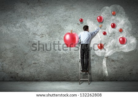 Businessman on ladder pointing at illustrated apple tree