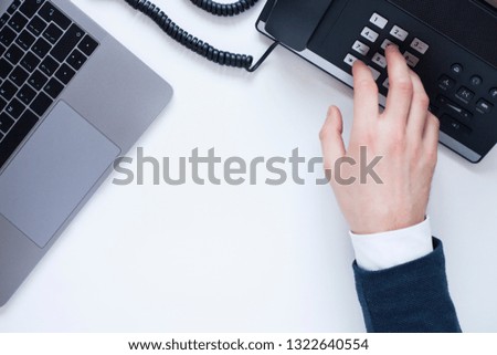 Male hand, laptop, IP phone, mobile phone and notebook on the white background. Top view. Ip telephony and video meetings for business concept. 