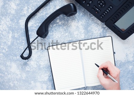 Male hand, laptop, IP phone, mobile phone and notebook on the gray  background. Top view. Ip telephony and video meetings for business concept. 