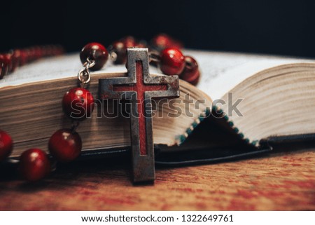 Old red Beads and crucifix on a Holy Bible background. Macro view.