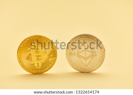Bitcoin and ether coin in gold and silver against a yellow background