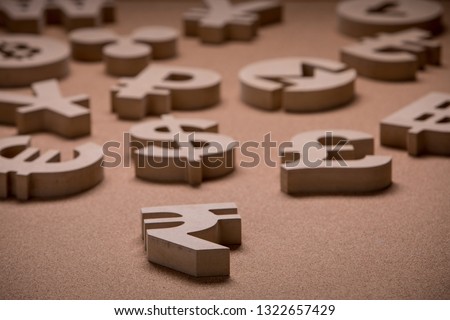 Wooden Symbols of World Currencies in Group Picture with Shallow Focus with Indian Rupee Sign in the Front