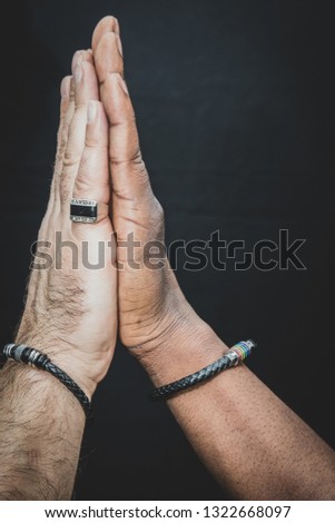 An interracial gay couple posing before the camera to have their pictures taken - black man and mixed race man - on black background - with copy space. 