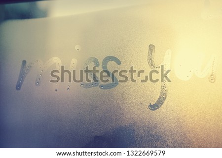 Miss you sign and foggy condensated window with blurry effect textured outdoors background, close up image