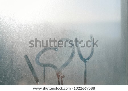 Love heart sign and foggy condensated window with blurry effect textured outdoors background, close up image