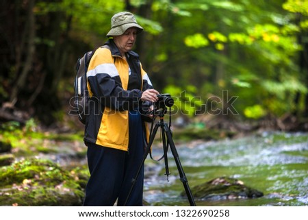 tourist with a camera on a tripod photographs a mountain river