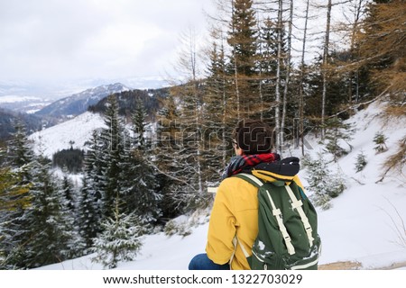 The traveler on the cliff in winter mountains