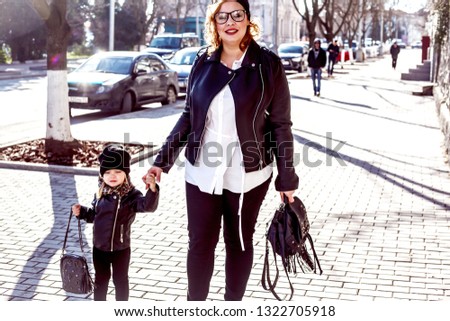 fashion family,in composition of mother and daughter walking a street