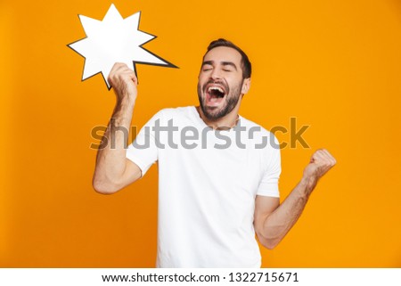 Photo of joyous man 30s in casual wear holding blank idea advertisement isolated over yellow background