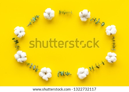 Flowers frame on yellow desk with fresh eucalyptus branches and cotton. Flat lay, top view, copy space
