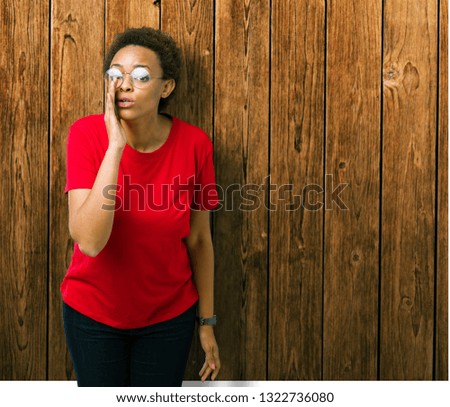 Beautiful young african american woman wearing glasses over isolated background hand on mouth telling secret rumor, whispering malicious talk conversation