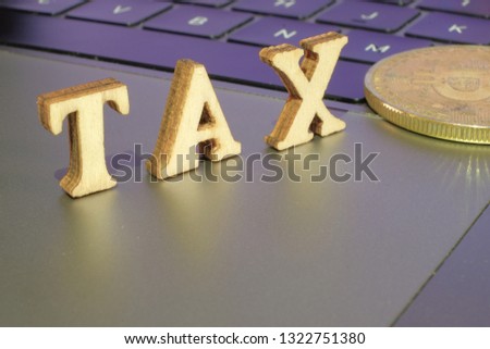 Bitcoin  and next to wooden with TAX letters. Bitcoin taxation concept