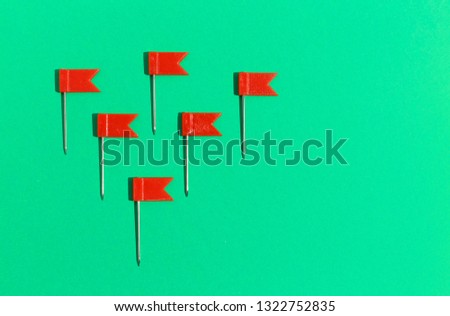 Red little flag pins on a green background. View from above