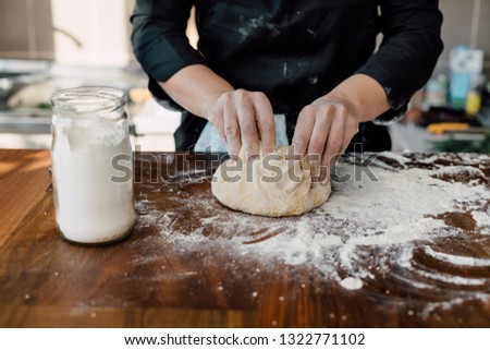 Female chef kneading dough in the kitchen