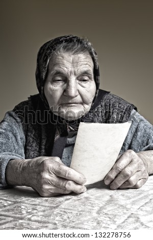 Elderly woman looking at old photos, reminisce about the past. Selective focus on photos.