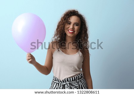 Beautiful young woman with balloon on light background