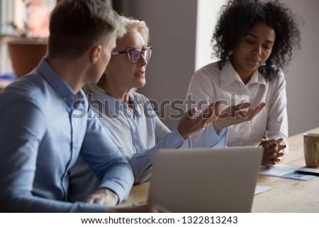 Mature businesswoman sharing ideas with colleagues at company meeting, dissatisfied team leader talking about business strategy, discussing bad project results or business failure at briefing Royalty-Free Stock Photo #1322813243