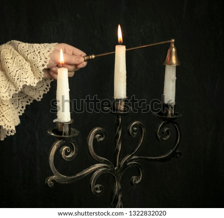 hand of a child puts out the flame of candles on a bronze candelabrum. Concept photo of vintage, home sweet home, knowledge of the world, education, authenticity