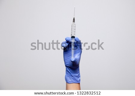 Closeup doctor's hand in rubber purple glove holding transparent syringe without cap. Isolated on white background. Concept of rejection of vaccinations, vaccination, rabies injection