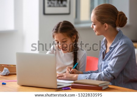 Cute girl with mother doing homework at home Royalty-Free Stock Photo #1322833595