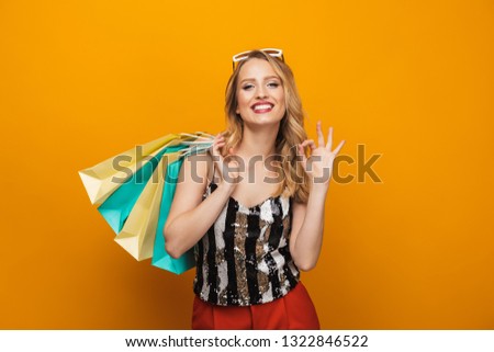 Portrait of a beautiful young blonde woman standing isolated over yellow background, ok