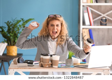 Stressed young businesswoman at table in office