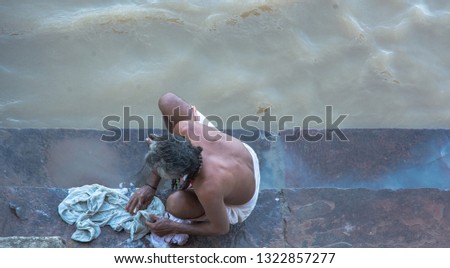 Man from behind washing clothes in the river Ganges, in Varanasi, India. Aerial photo
