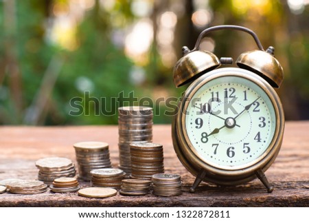 Vintage golden alarm clock with stacks of coin. Time and money for financial concept. Copy space. Royalty-Free Stock Photo #1322872811