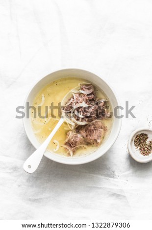 Simple beef broth with beef meat, onion and pepper on a light background, top view. Healthy food, soup base