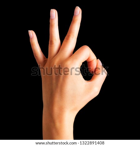 Woman holding hand in gesture of okay. Sign of success, victory or luck on black background. Isolated with clipping path.