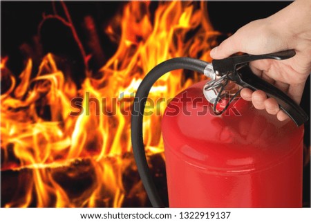 Red fire extinguisher and flames, close-up view